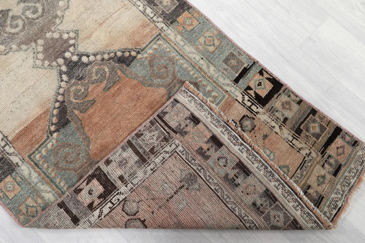 Corner of the rug folded back, showing the cotton foundation and the reverse side of the knotting.