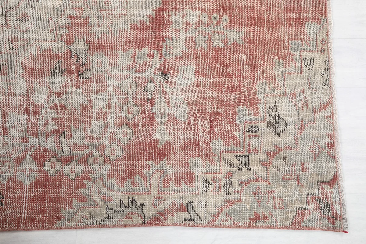 Detailed view of a corner of the rug, highlighting the faded geometric patterns and texture