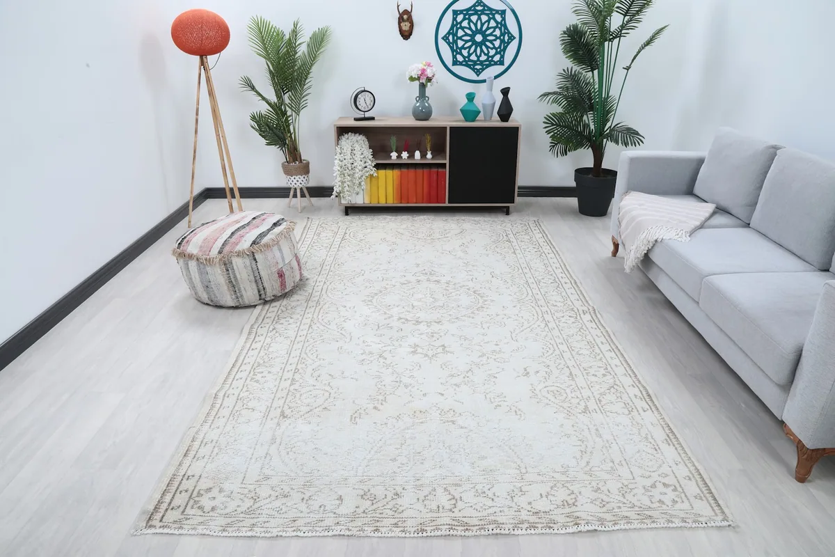 Vintage Anatolian area rug displayed in a bright living room setting with a sofa and ottoman