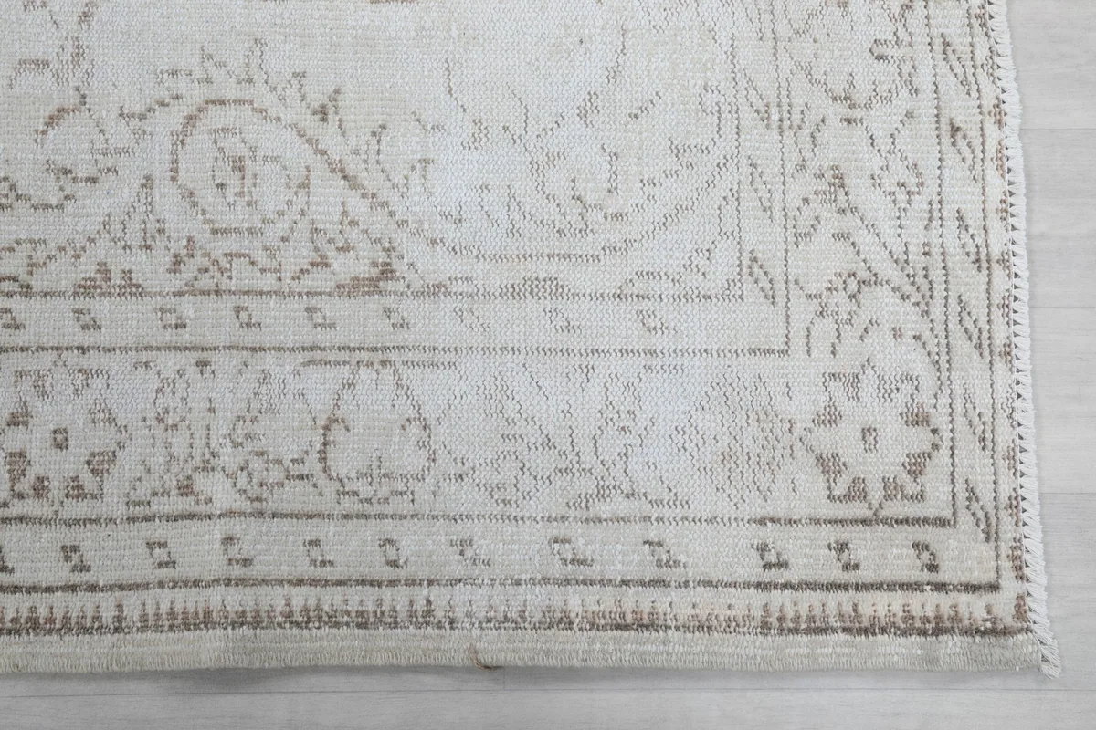 Detailed view of one corner of the rug, highlighting the tan geometric border and field patterns