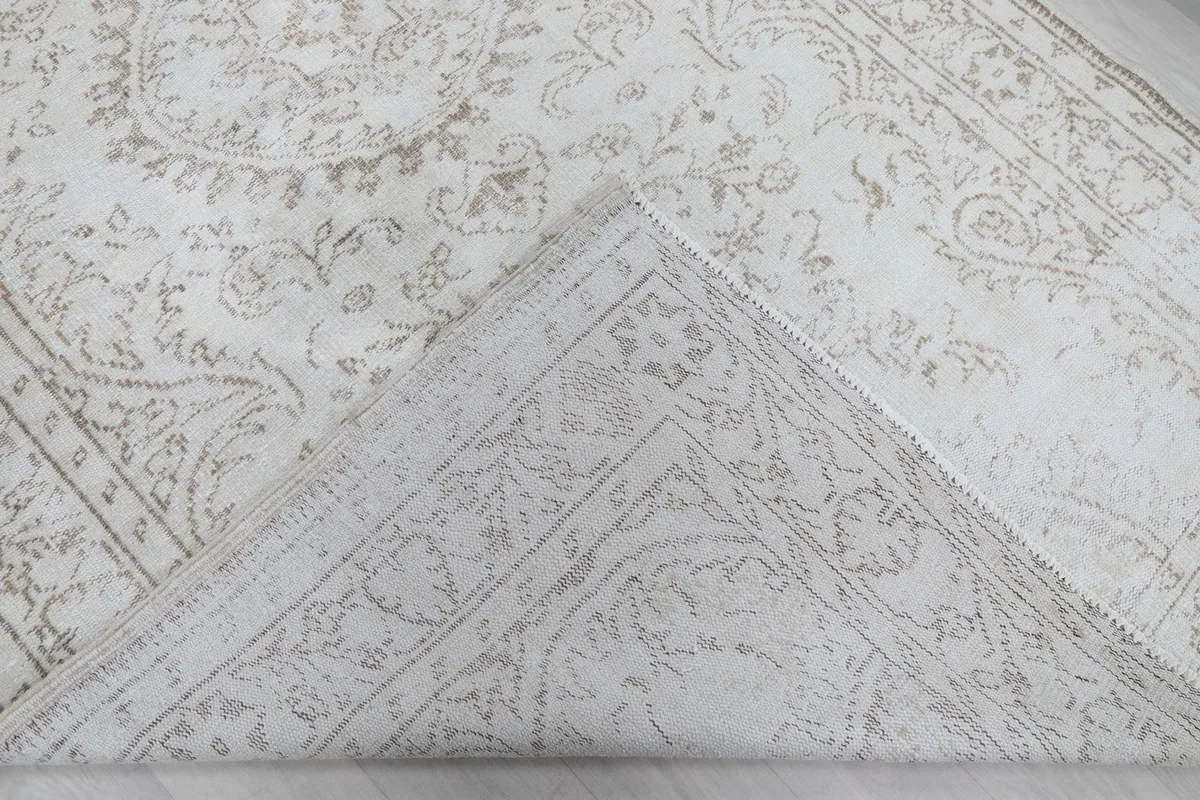 Corner of the rug folded back to reveal the cotton foundation and reverse side of the hand-knotted construction