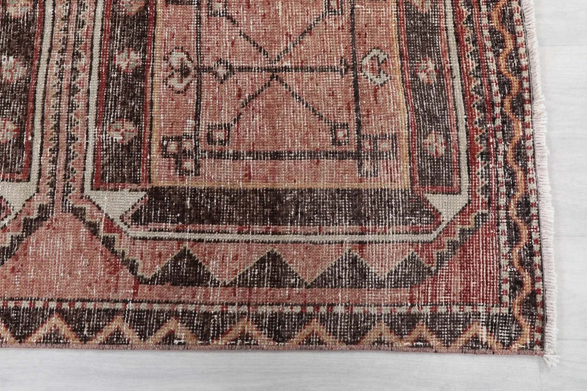 Detail view of the rug's border and a geometric medallion, showcasing the distressed texture and colors.