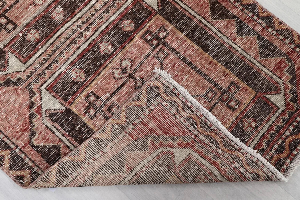 Folded corner of the rug, revealing the cotton foundation and the reverse side of the hand-knotting.