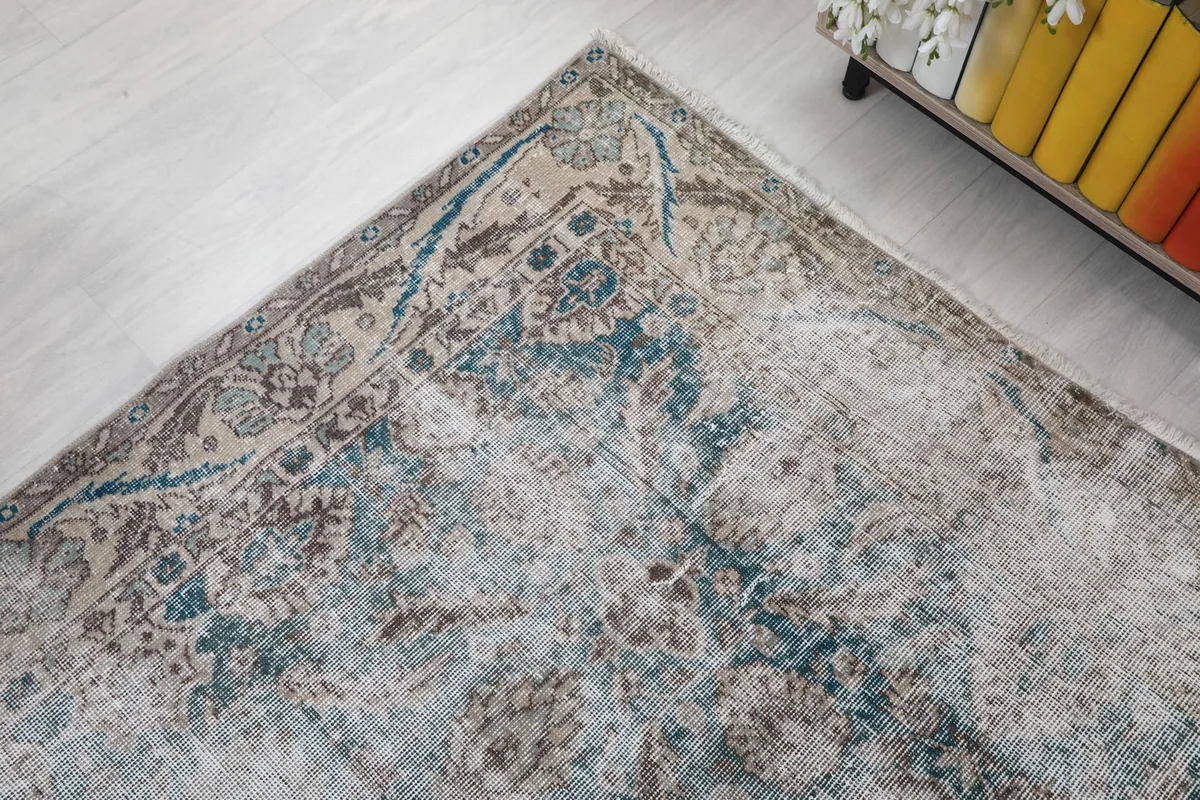 Corner detail of the rug, emphasizing the worn patterns and muted color palette