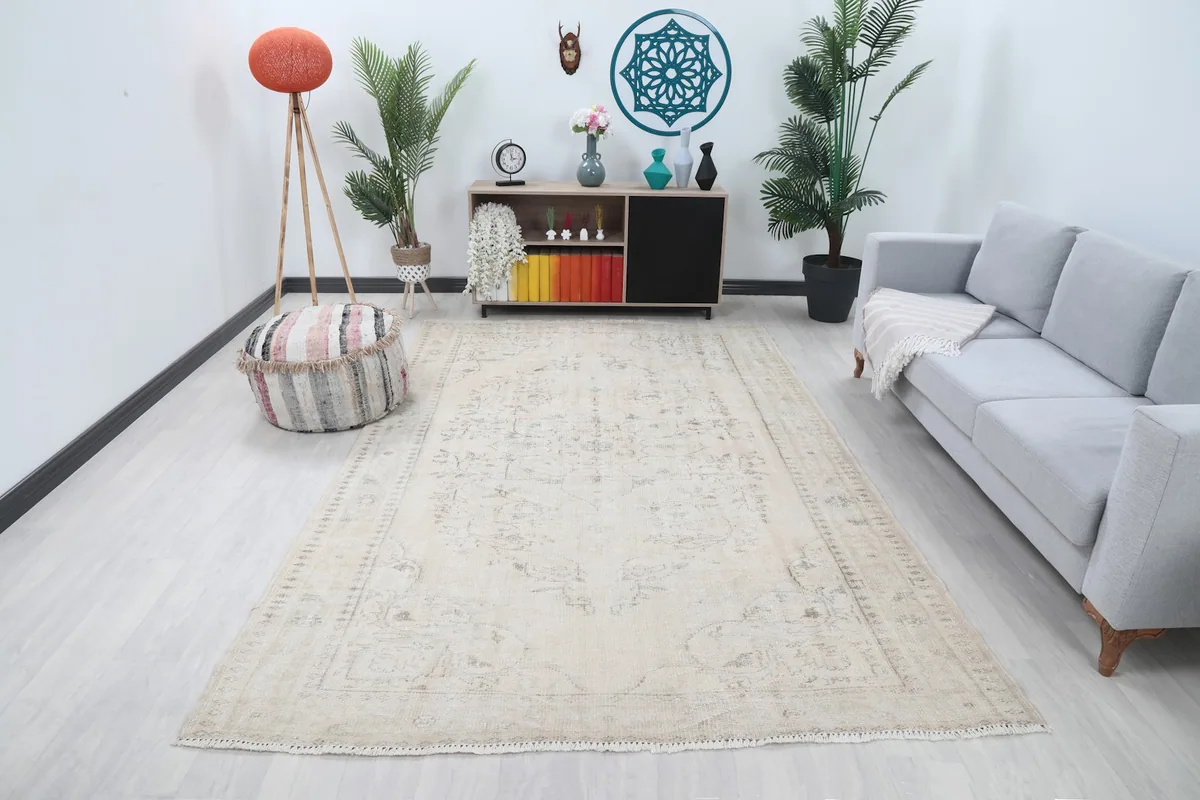 Ivory floral medallion rug displayed in a bright living space with a gray sofa and plants.