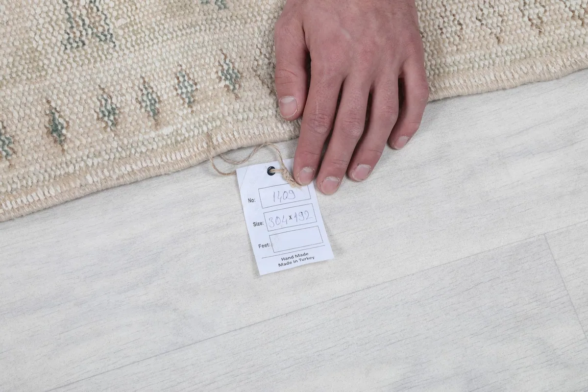 Hand holding a tag near the edge of the rug, demonstrating its quality and origin.