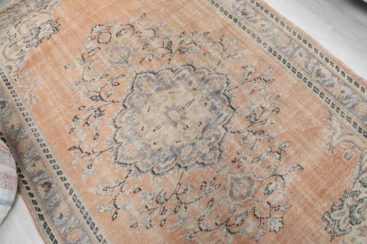 Overhead view focusing on the central medallion and faded orange field of the area rug