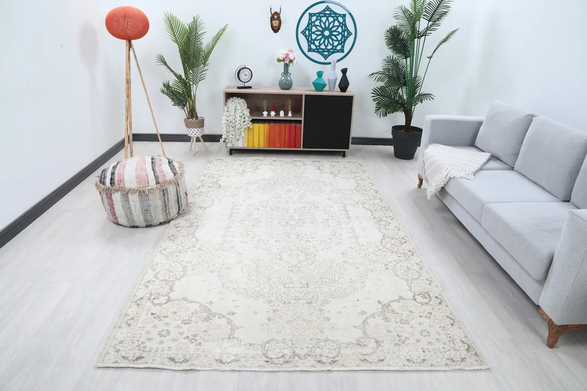 Ivory and beige vintage rug displayed in a bright living room setting with a light gray sofa