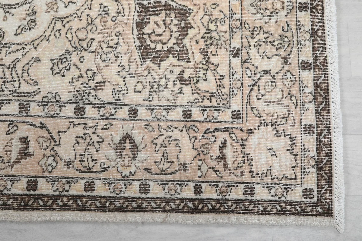 Detailed view of the brown outer border and corner design of the vintage rug