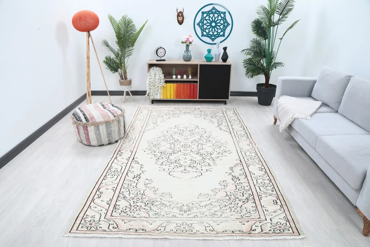 Vintage Anatolian rug displayed in a room with a light gray sofa and wooden furniture.