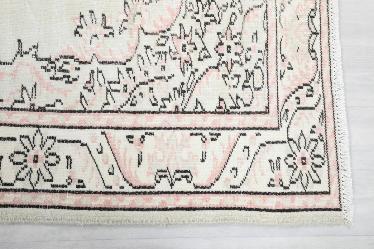Close-up detail of the rug's corner, showing the rose and black border patterns.