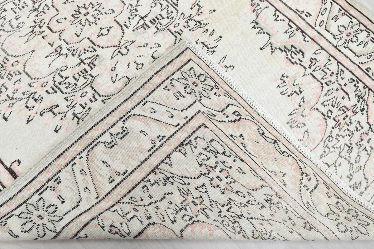 Corner of the rug folded to show the hand-knotted cotton foundation and wool pile reverse.