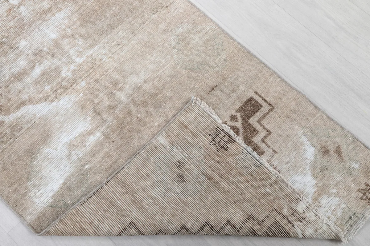 Corner view of the rug flipped to show the cotton foundation and reverse side of knotting.