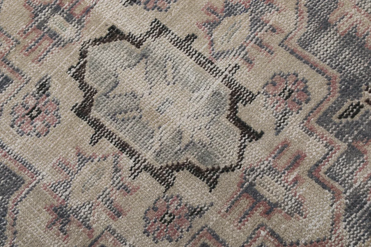Detail of the rug's pile and weaving, showing the blend of gray, beige, and rose fibers.