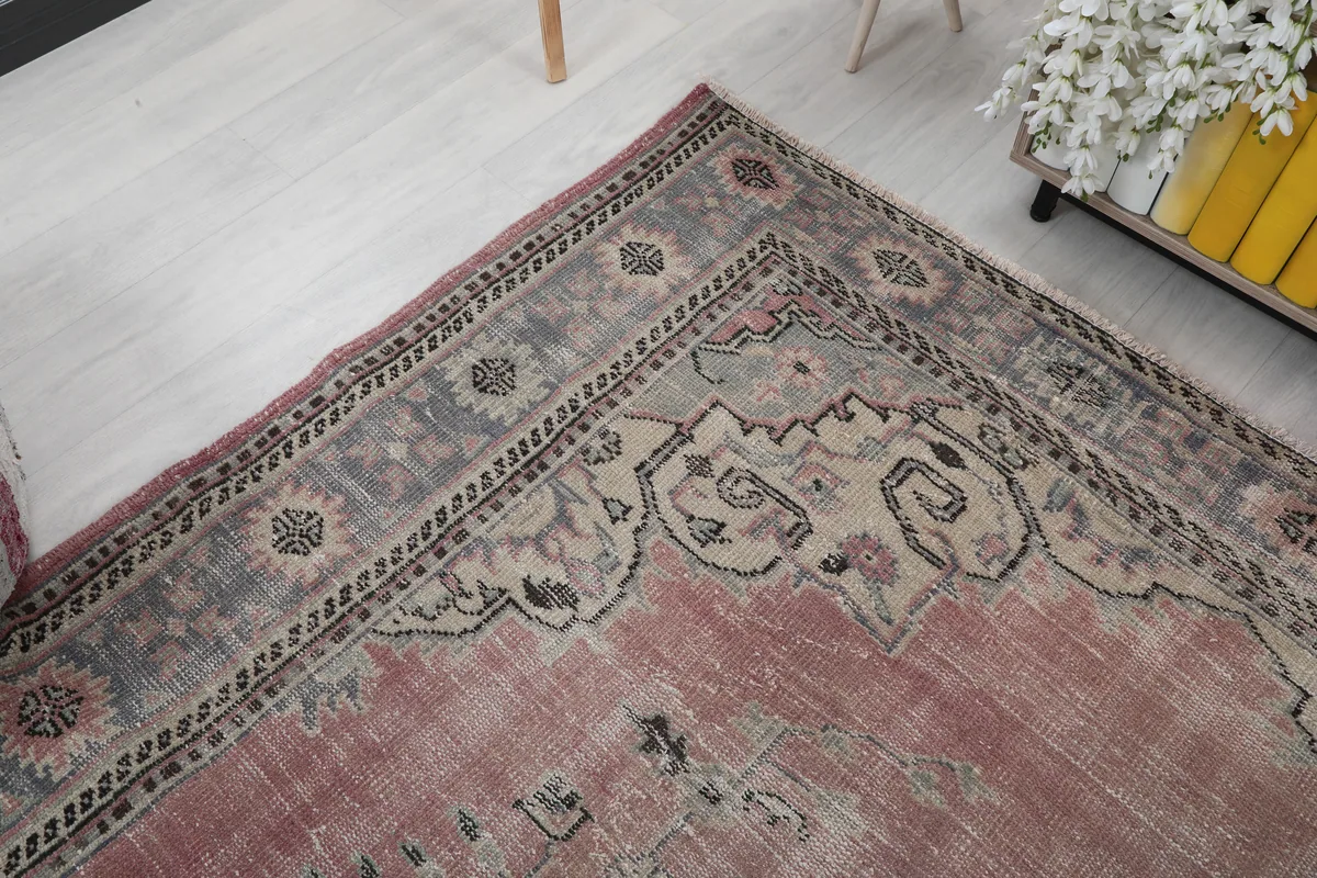 Corner detail of the rug's border, showcasing the gray and beige patterns and rose field.