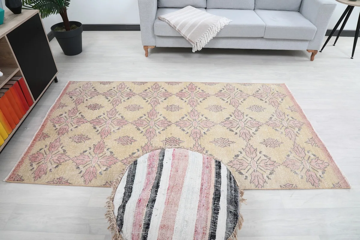 Overhead view of the rug in a room, with a pouf and sofa, showing its full design
