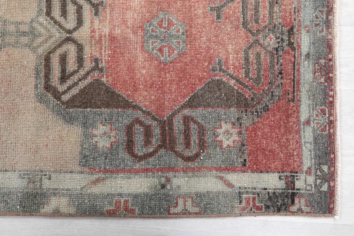 Close-up detail of the rug's end, showing the red and gray border and tribal motifs.