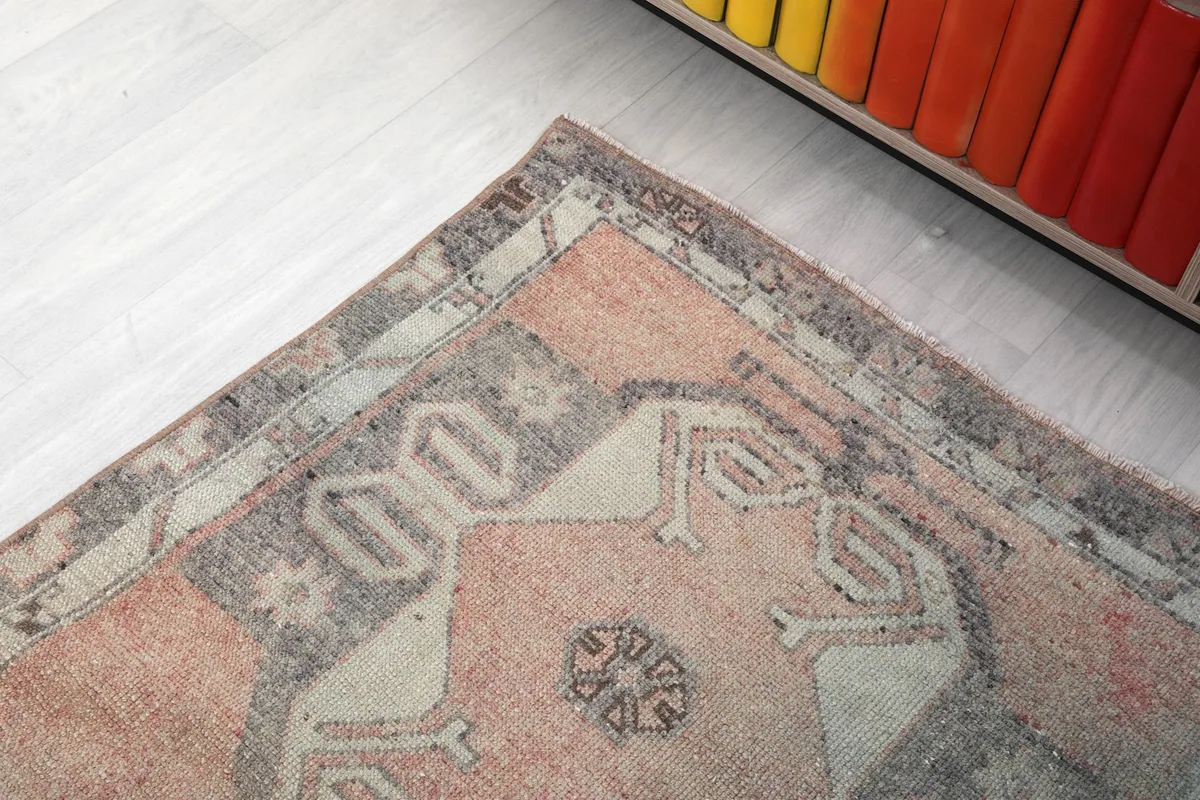 Detail of the rug's border and corner, showing the intricate gray and beige patterns.