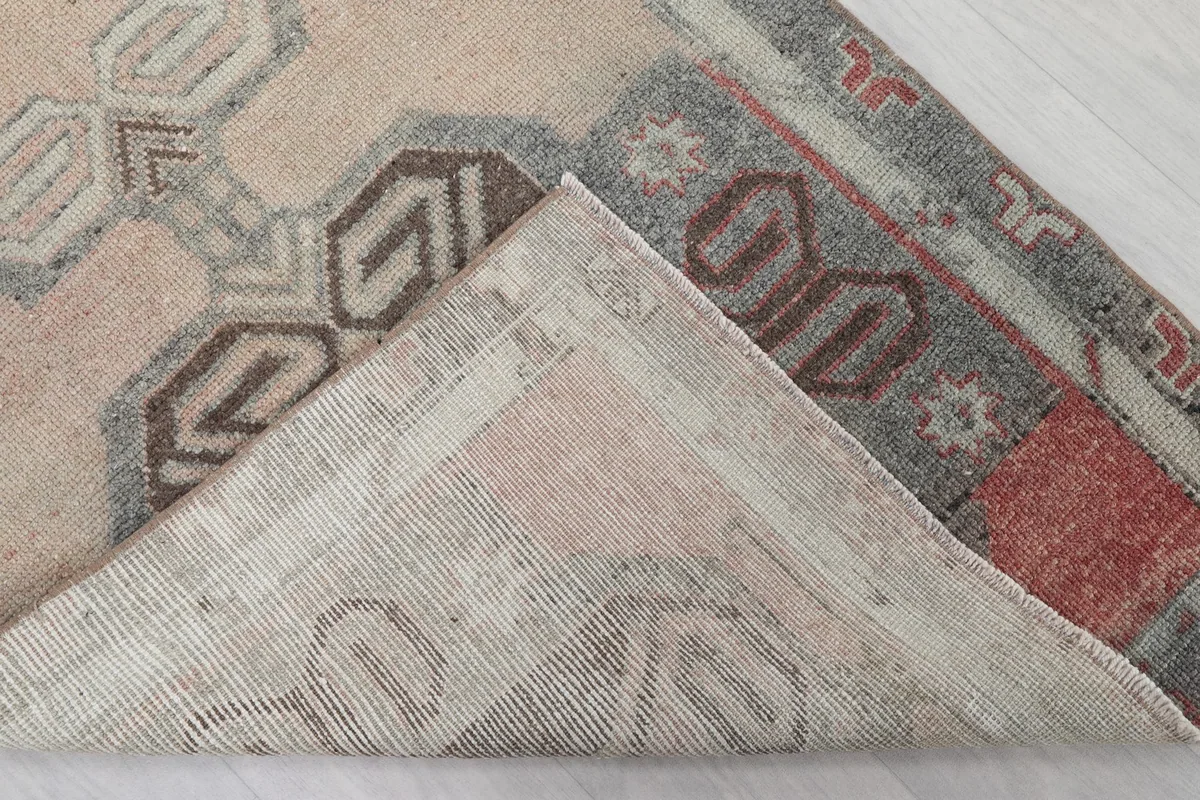 Folded corner showing the back of the hand-knotted wool rug, revealing the cotton foundation.