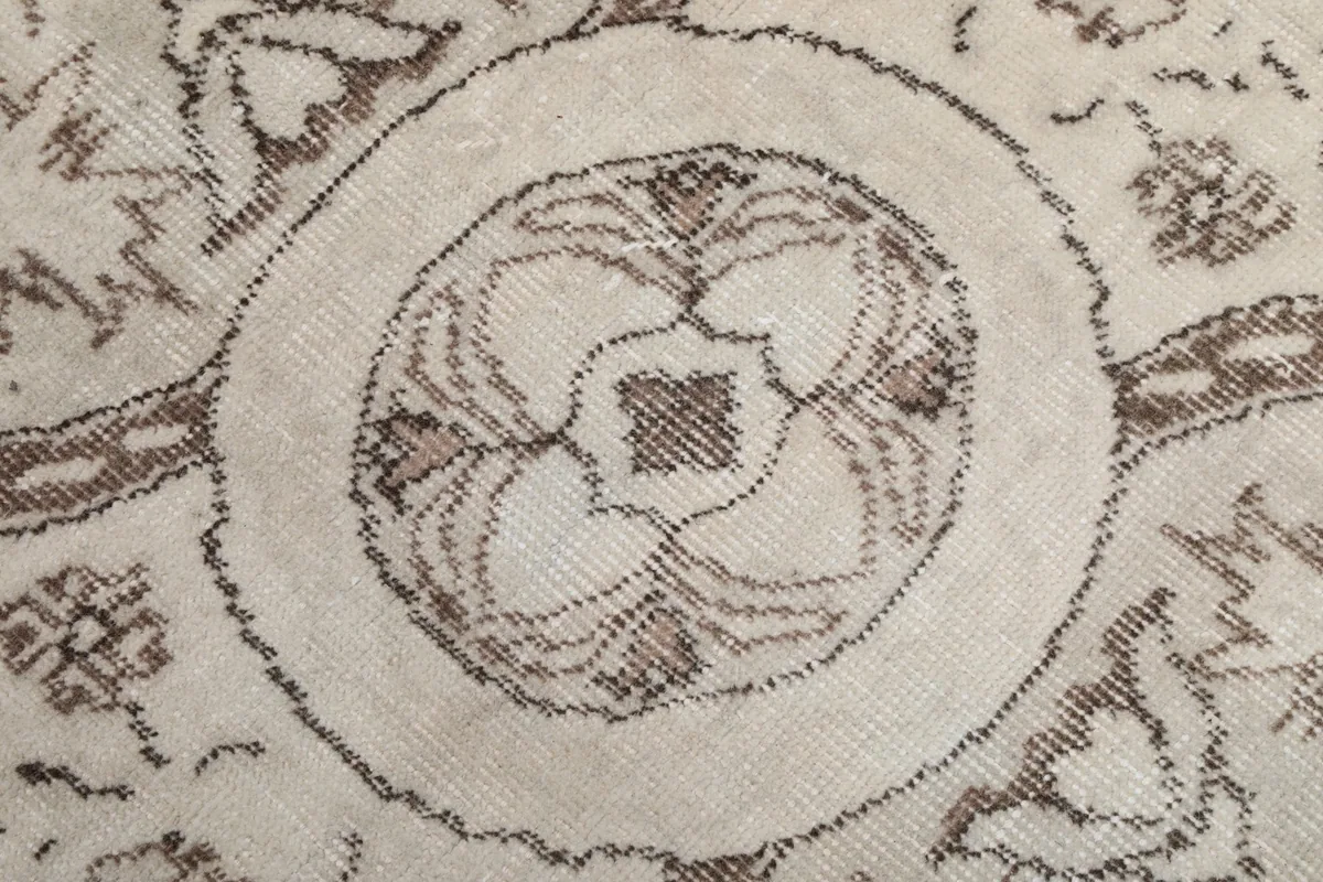 Close-up of the central round medallion detail with brown outlines and ivory center