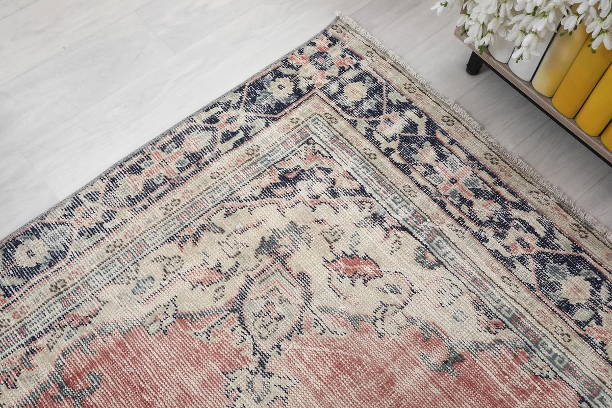 Corner detail of the rug, showing the blend of rose, navy, and ivory colors in the motifs.
