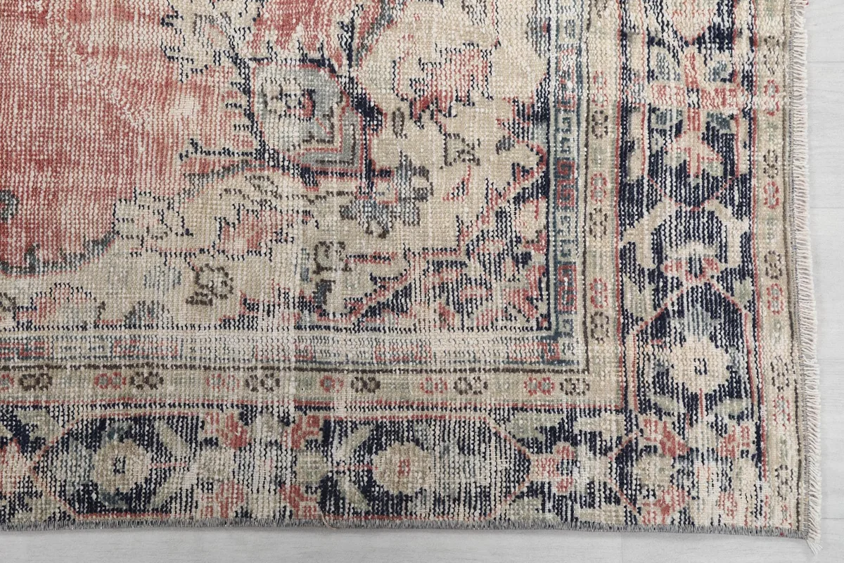 Detail of the rug's border pattern in navy and ivory, with visible wear and patina.