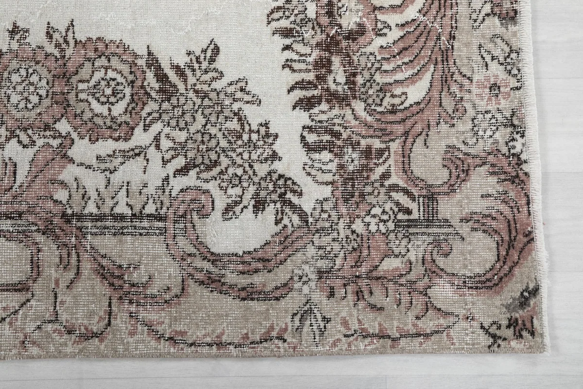 Detailed view of the intricate floral and scrollwork border in rose and tan