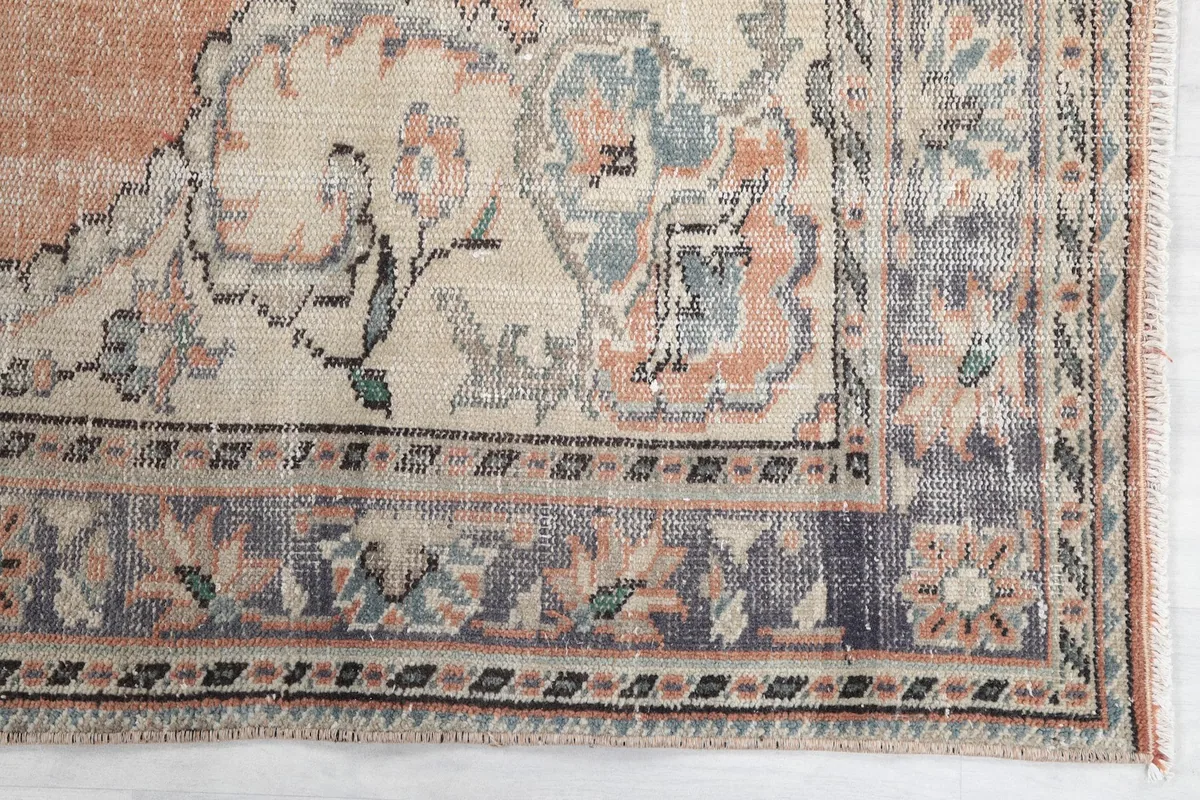 Detailed view of the rug's border pattern and corner motifs in ivory and blue