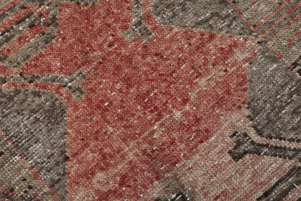 Extreme close-up of the hand-knotted wool pile, showing the texture and variegated rose color.