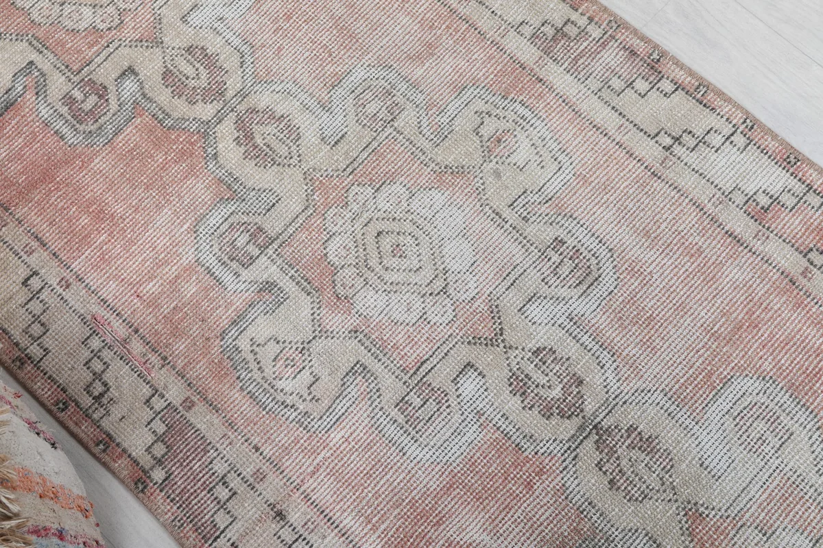 Close-up of the central medallion-like geometric motif in ivory and gray on the rose field
