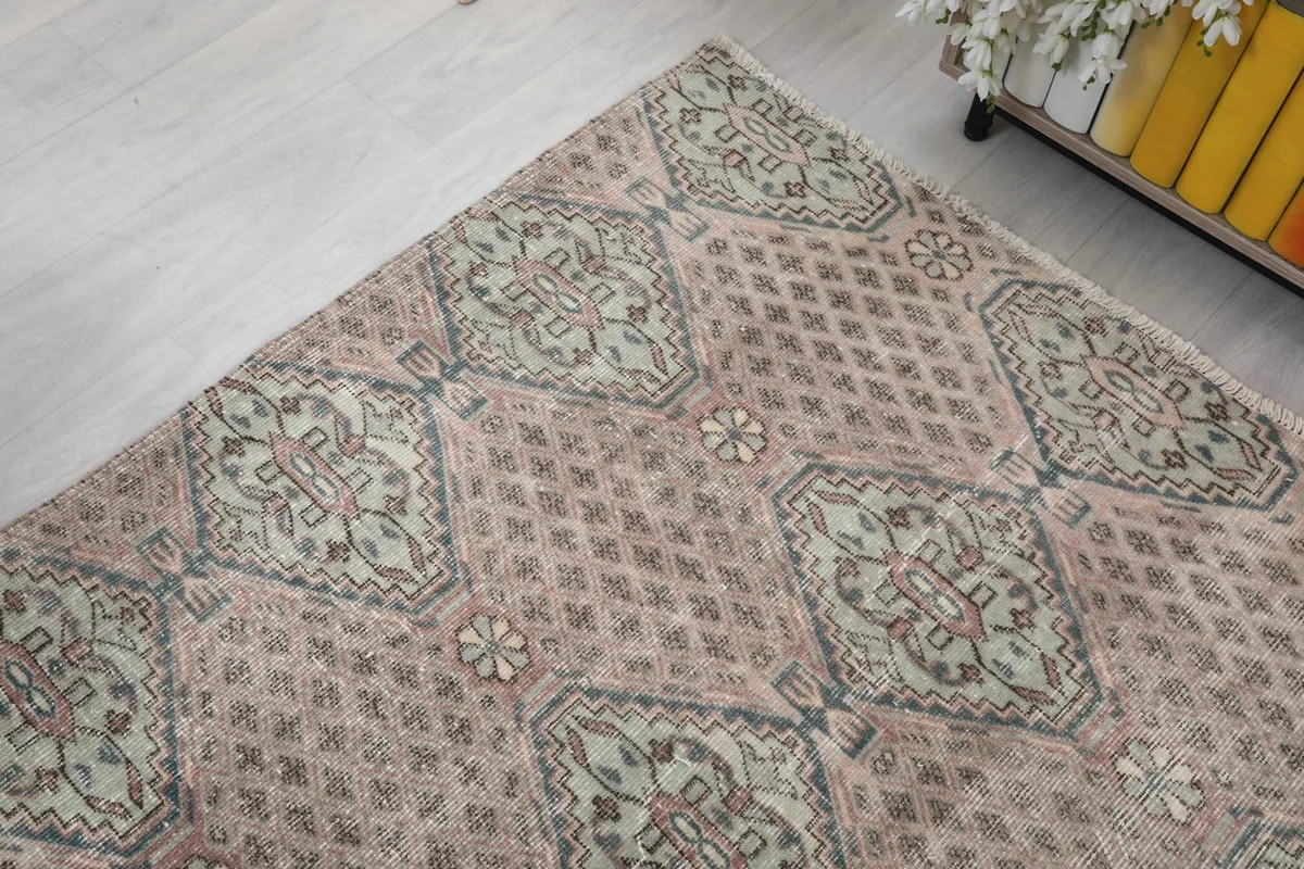 Corner view of the rug, showcasing the interplay of rose and gray tones and the geometric design.