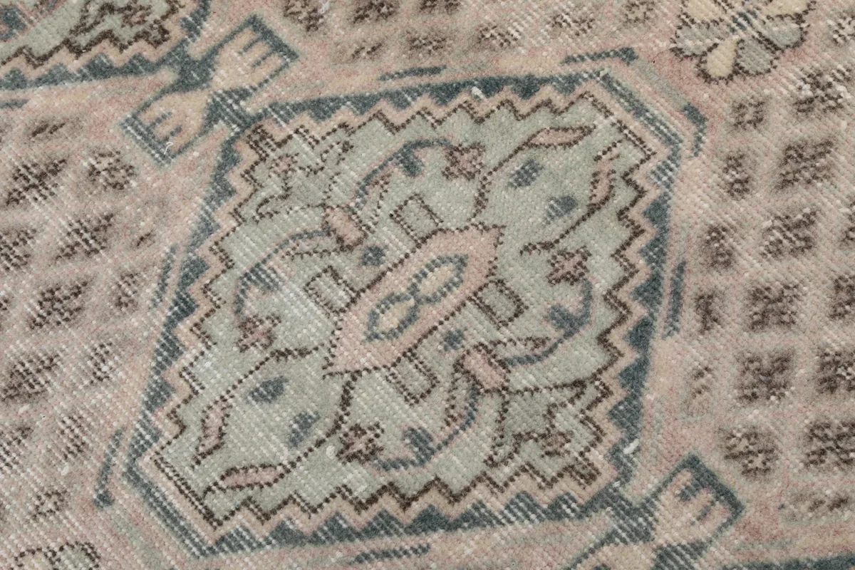 Extreme close-up of a single geometric motif on the rug, showing knotting detail and color variations.