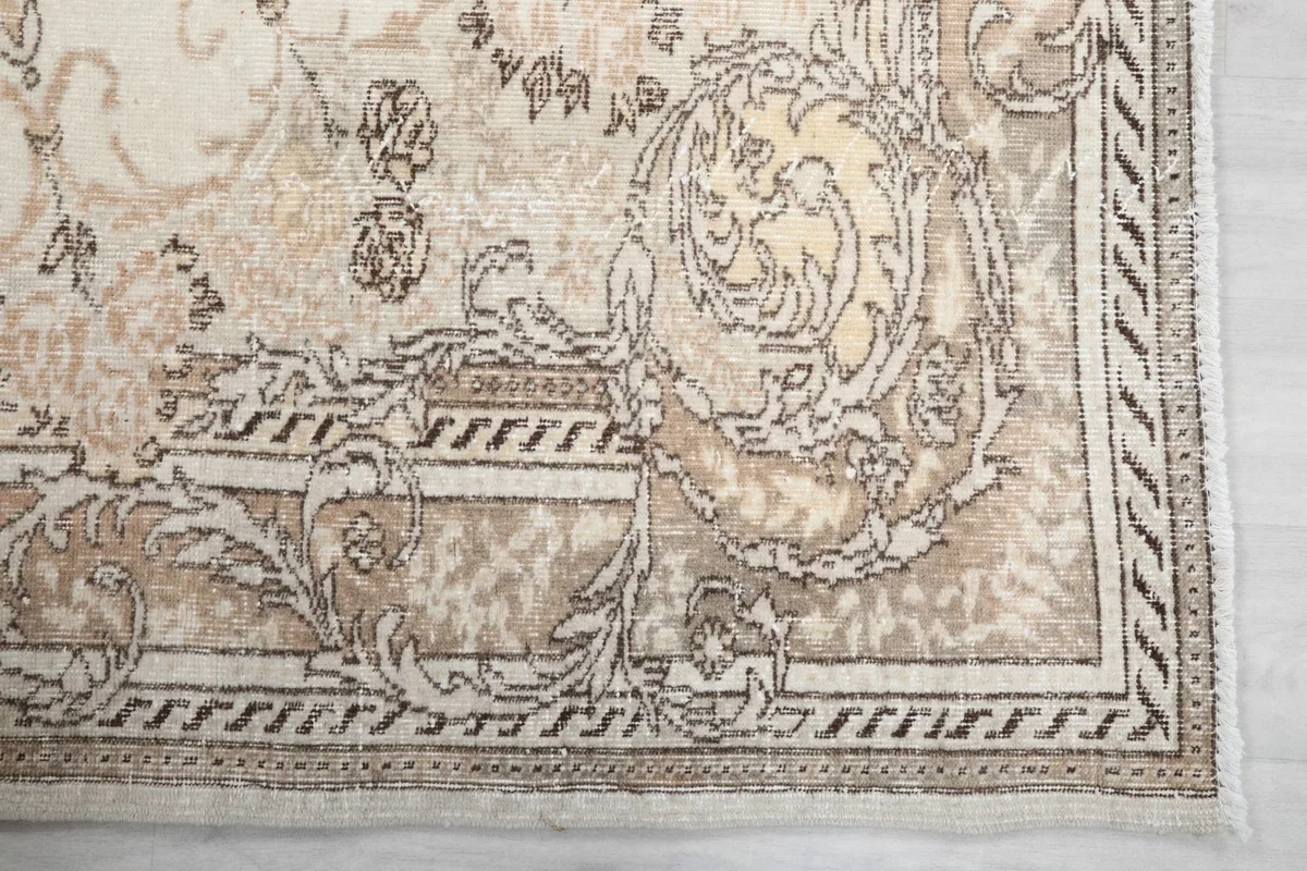 Close-up of the intricate beige and brown floral border pattern on the vintage rug