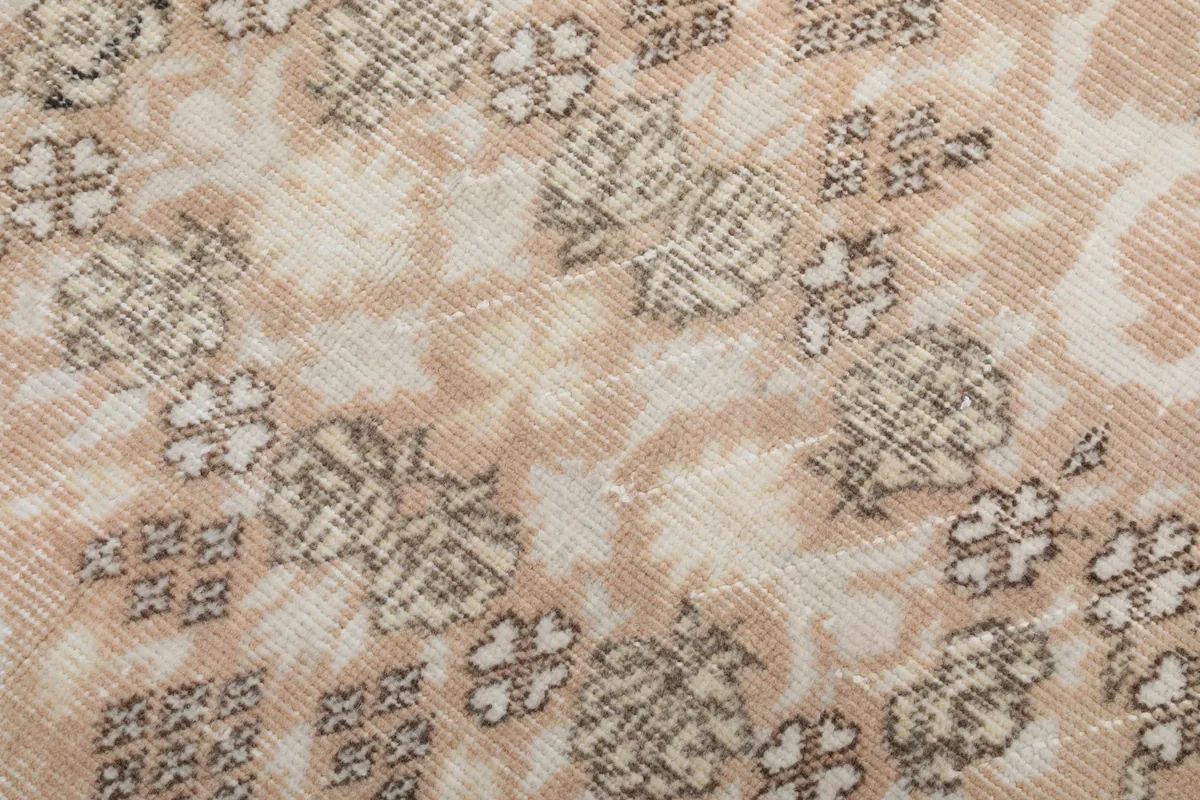 Macro view of the hand-knotted wool pile showing texture and softened colors of the rug