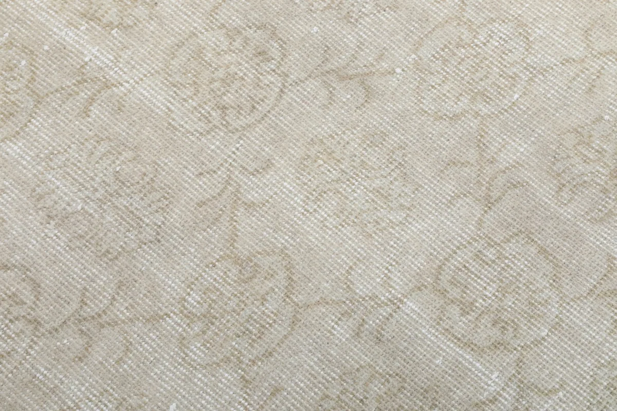 Close-up of the hand-knotted wool pile, showing the intricate yet faded floral design.