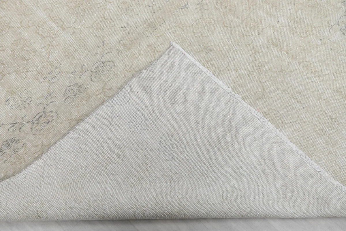 Corner of the rug folded back to reveal the cotton foundation and the reverse side of the knotting.