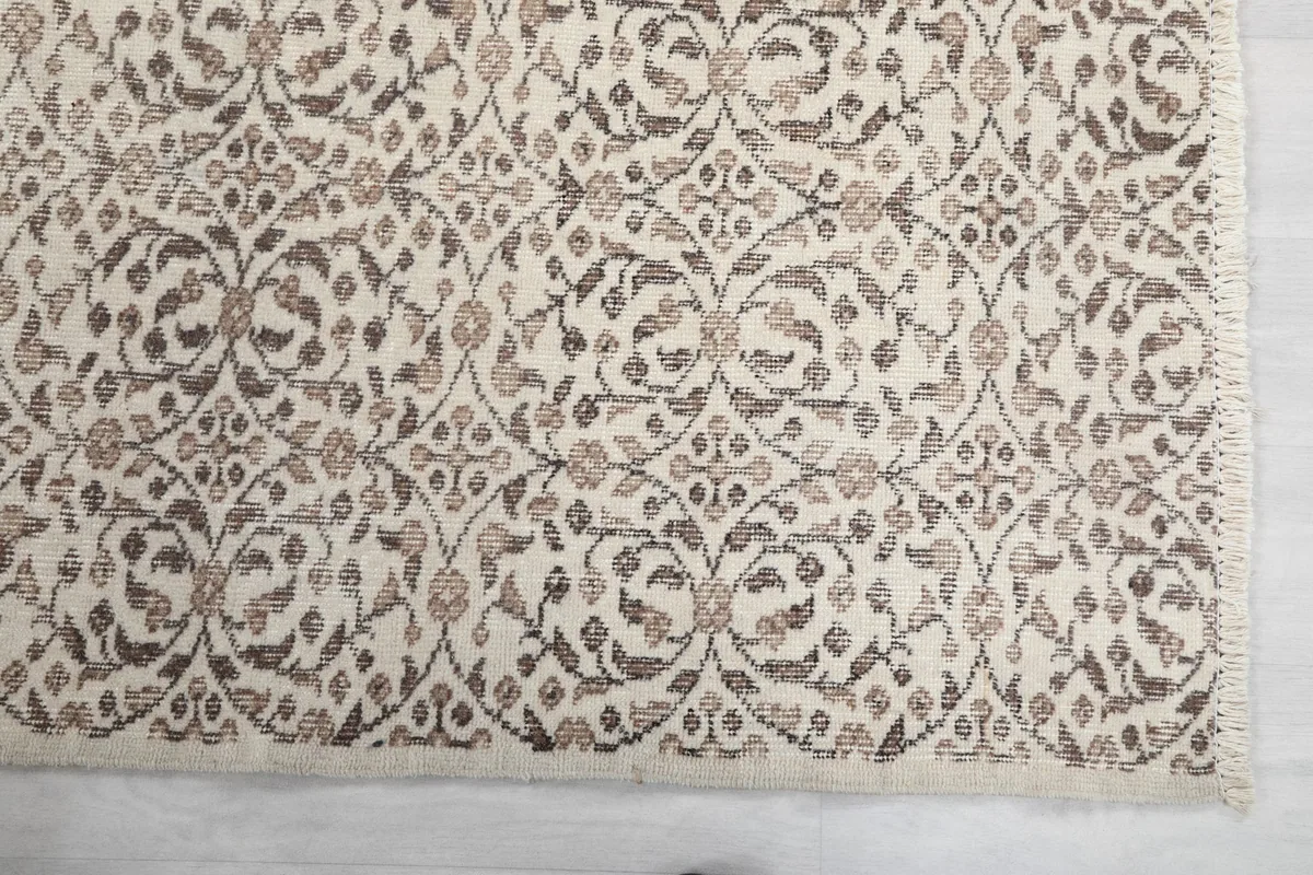 Close-up detail of the hand-knotted floral and geometric patterns on the rug's corner