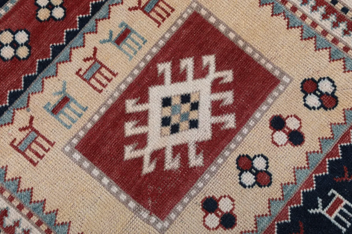 Close-up of a red geometric medallion on a cream field, with surrounding tribal elements.
