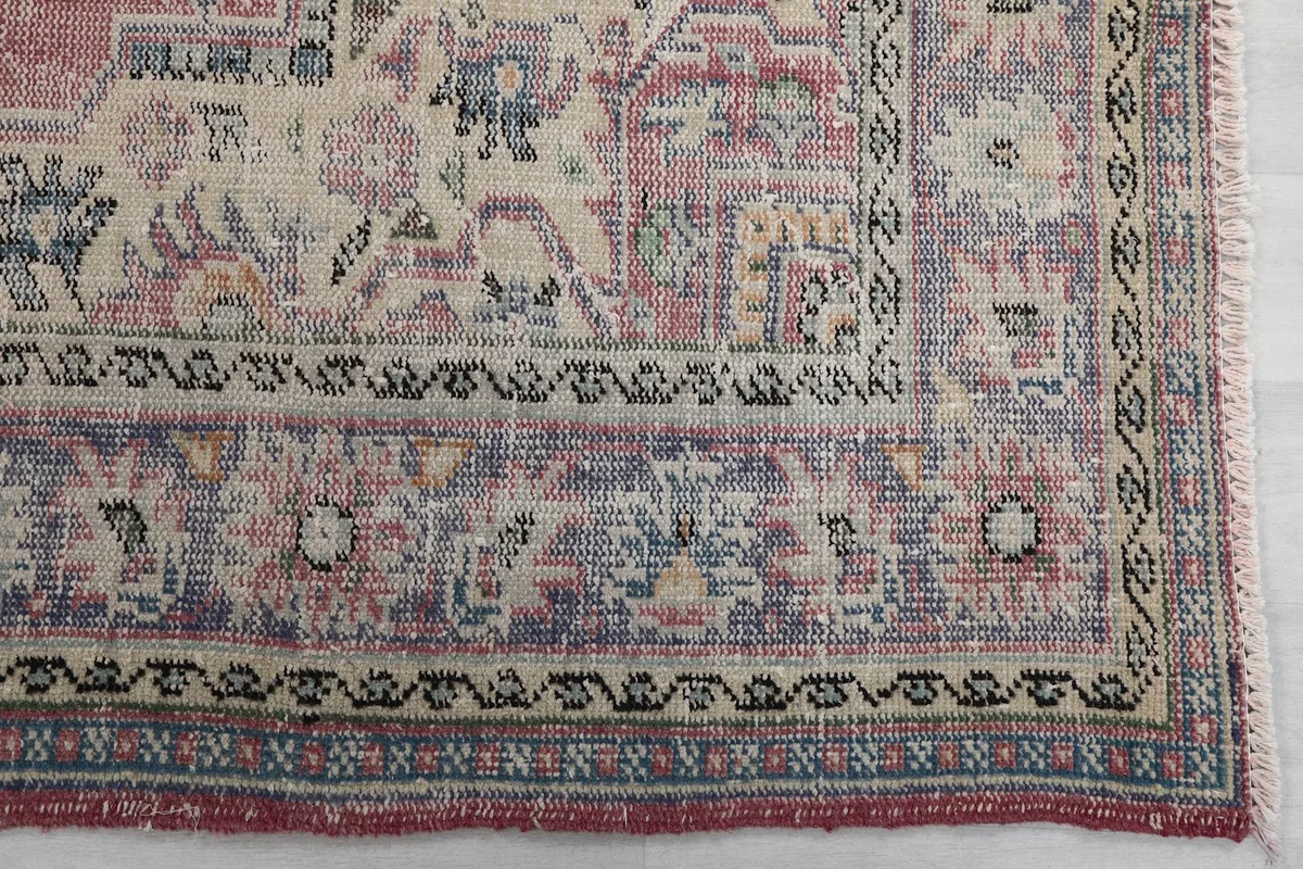 Detail of the outer border design with blue, beige, and black patterns on the vintage rug