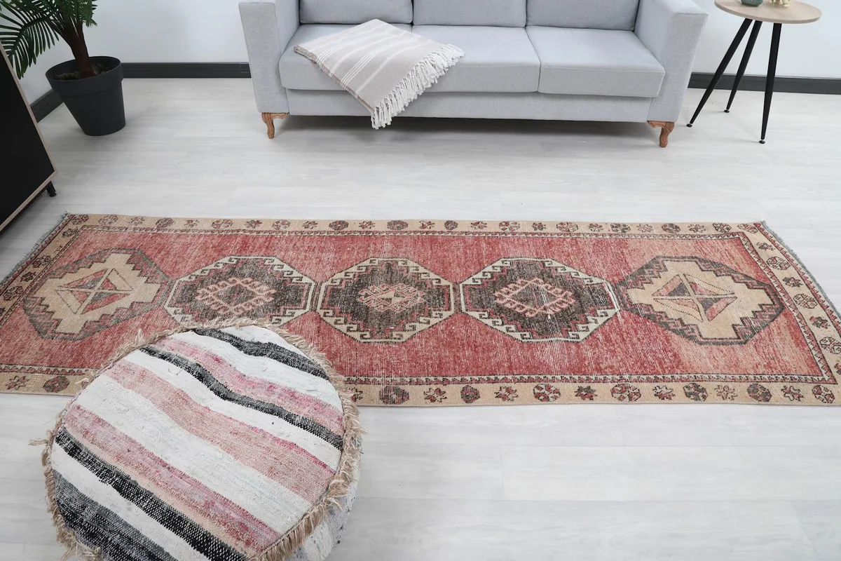 Full view of the runner rug in a room setting with a gray sofa and striped pouf