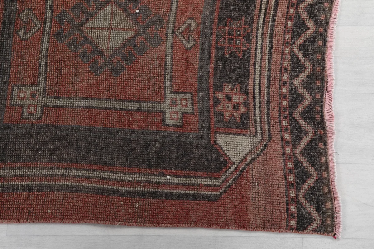 Detail of the rug's corner, highlighting the charcoal and beige geometric motifs and border design.