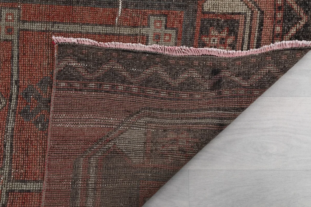 Close-up of the folded rug showing the cotton foundation and the reverse side of the hand-knotted weave.