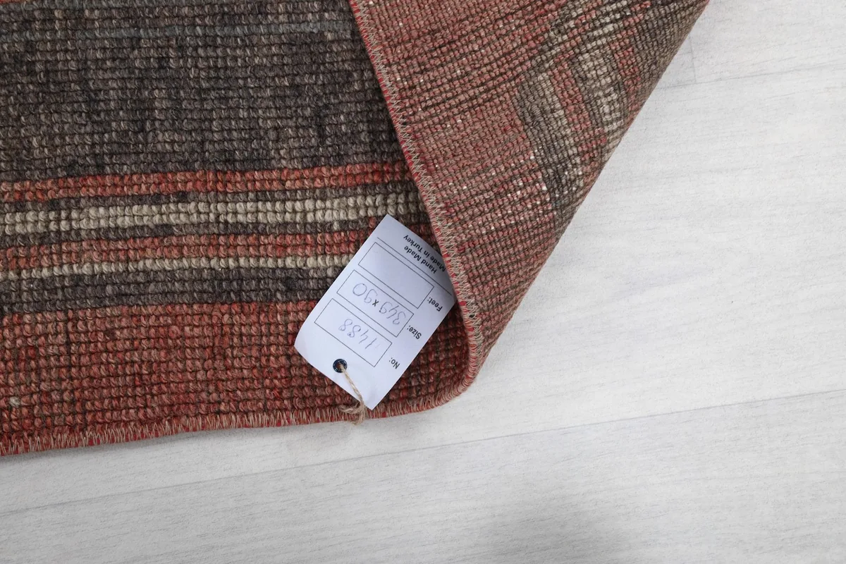 Underside of the rug with a tag, showing the tightly woven cotton foundation and wool pile.