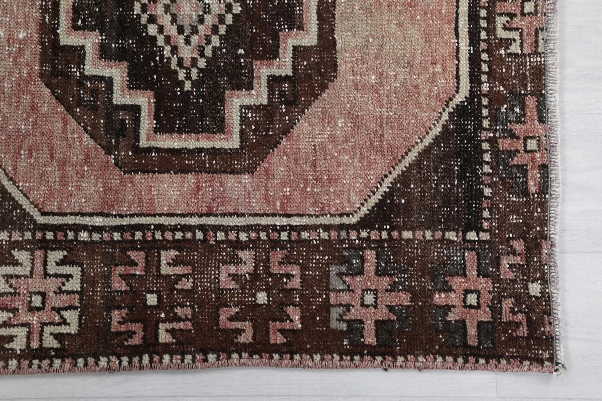 Detail view of the geometric border and a medallion with rose and brown tones