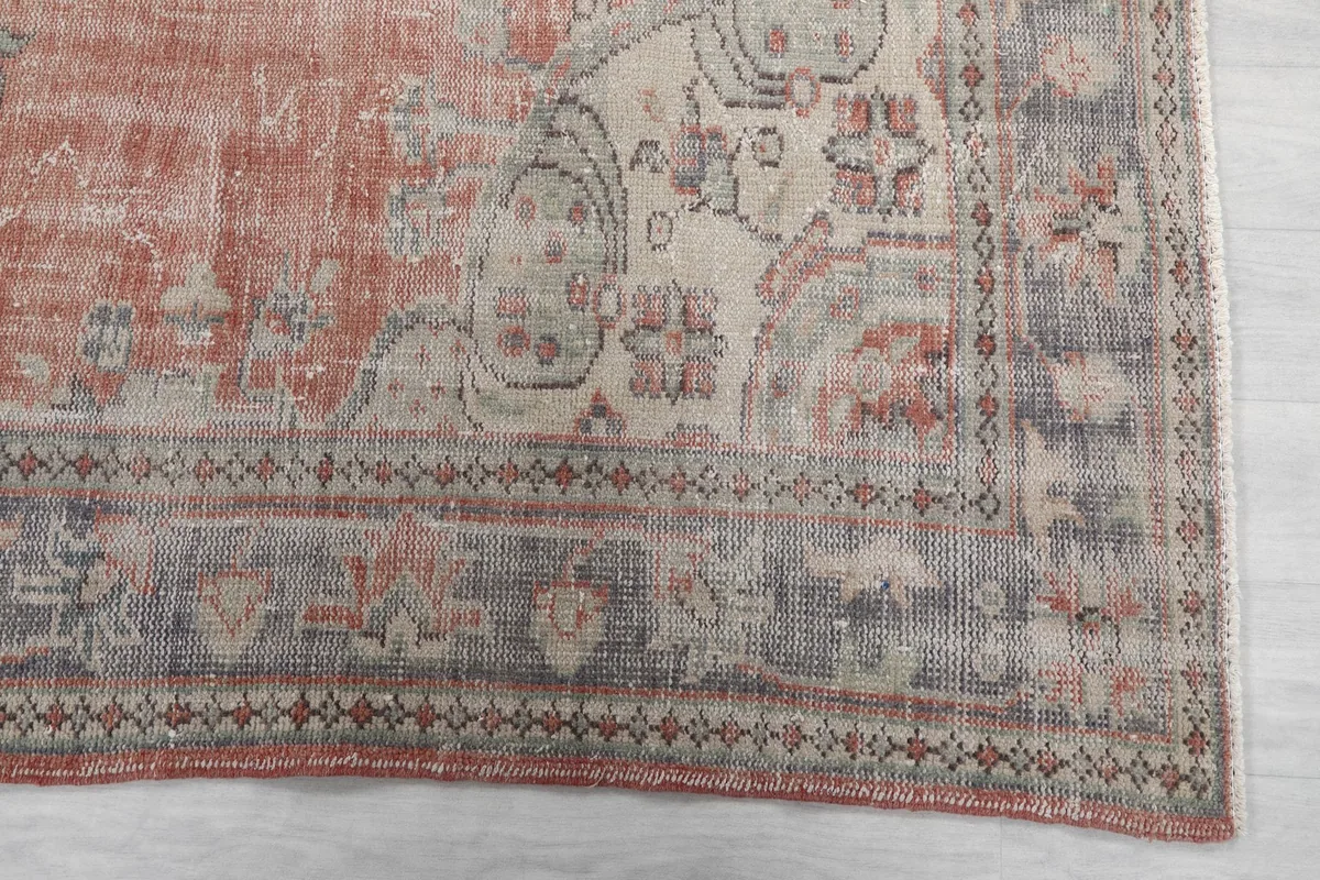 Close-up of the rug's border, showing intricate gray and beige patterns with a rust outer edge