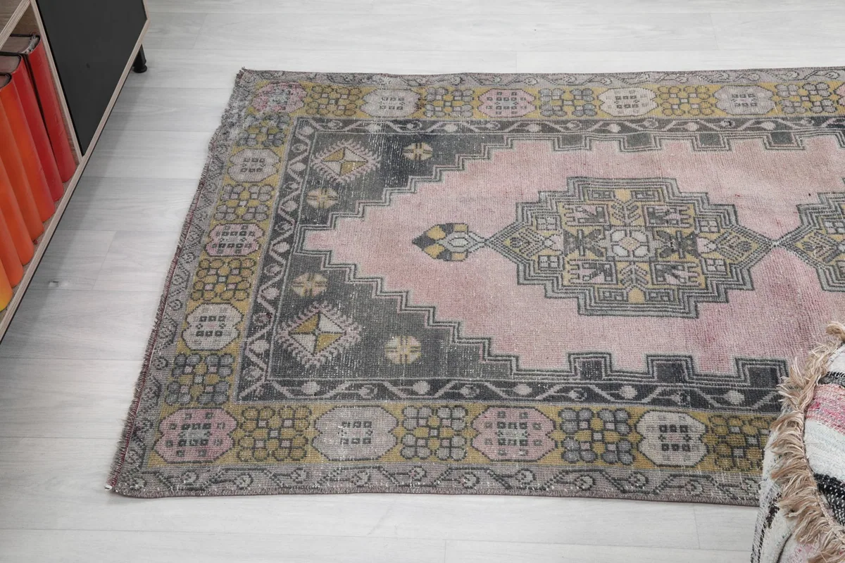 Angled view of the rug's length, showing the pink field and gray borders