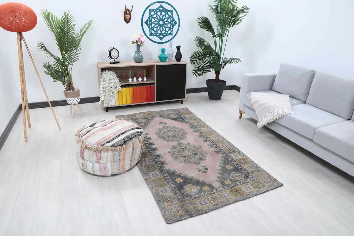 Room view showing the pink Anatolian rug with a decorative ottoman and minimalist furniture