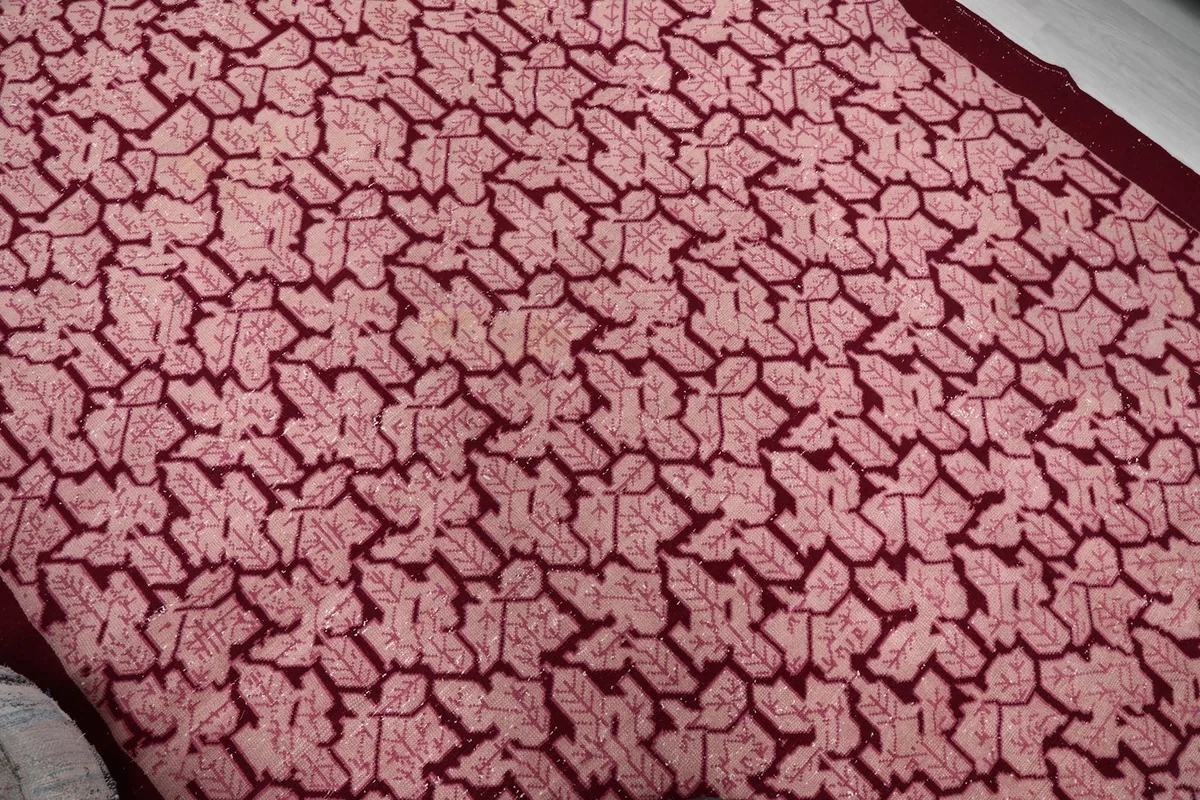 Close-up of the rose geometric motif and subtle color variations on the vintage rug