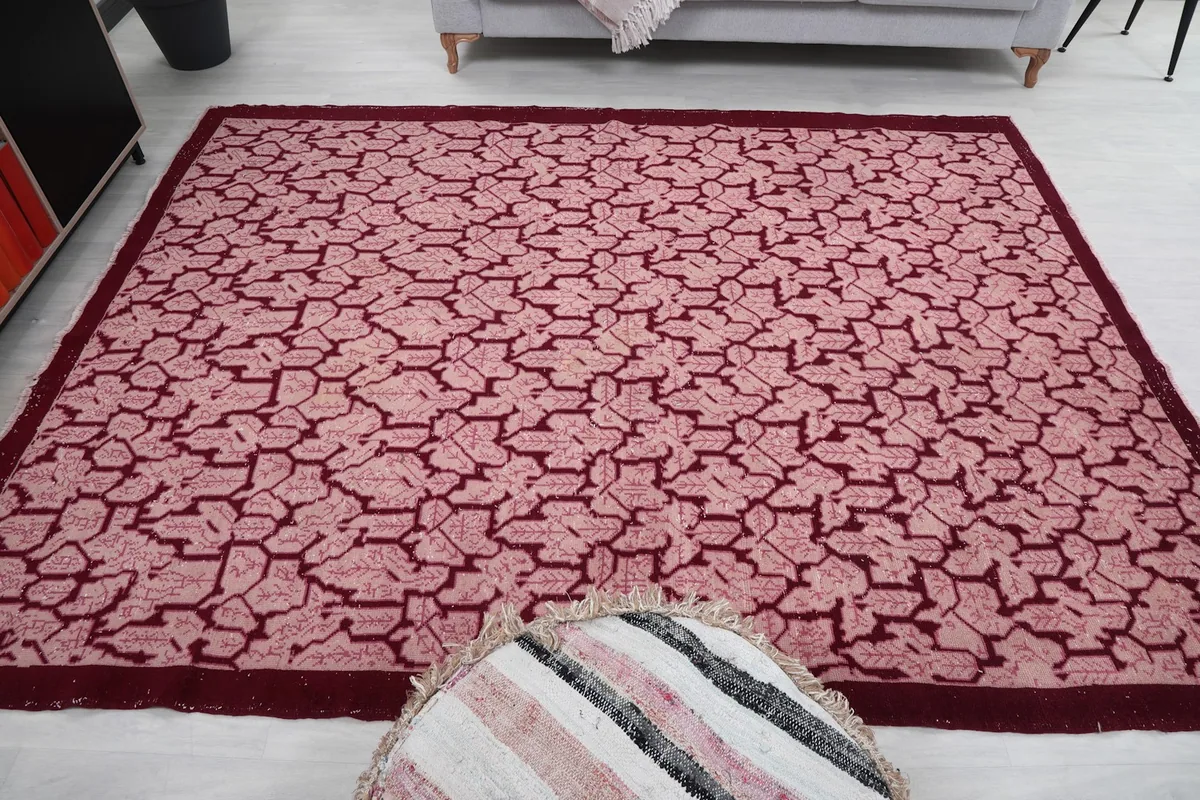 Overhead shot of the rose and red vintage rug with a decorative pouf