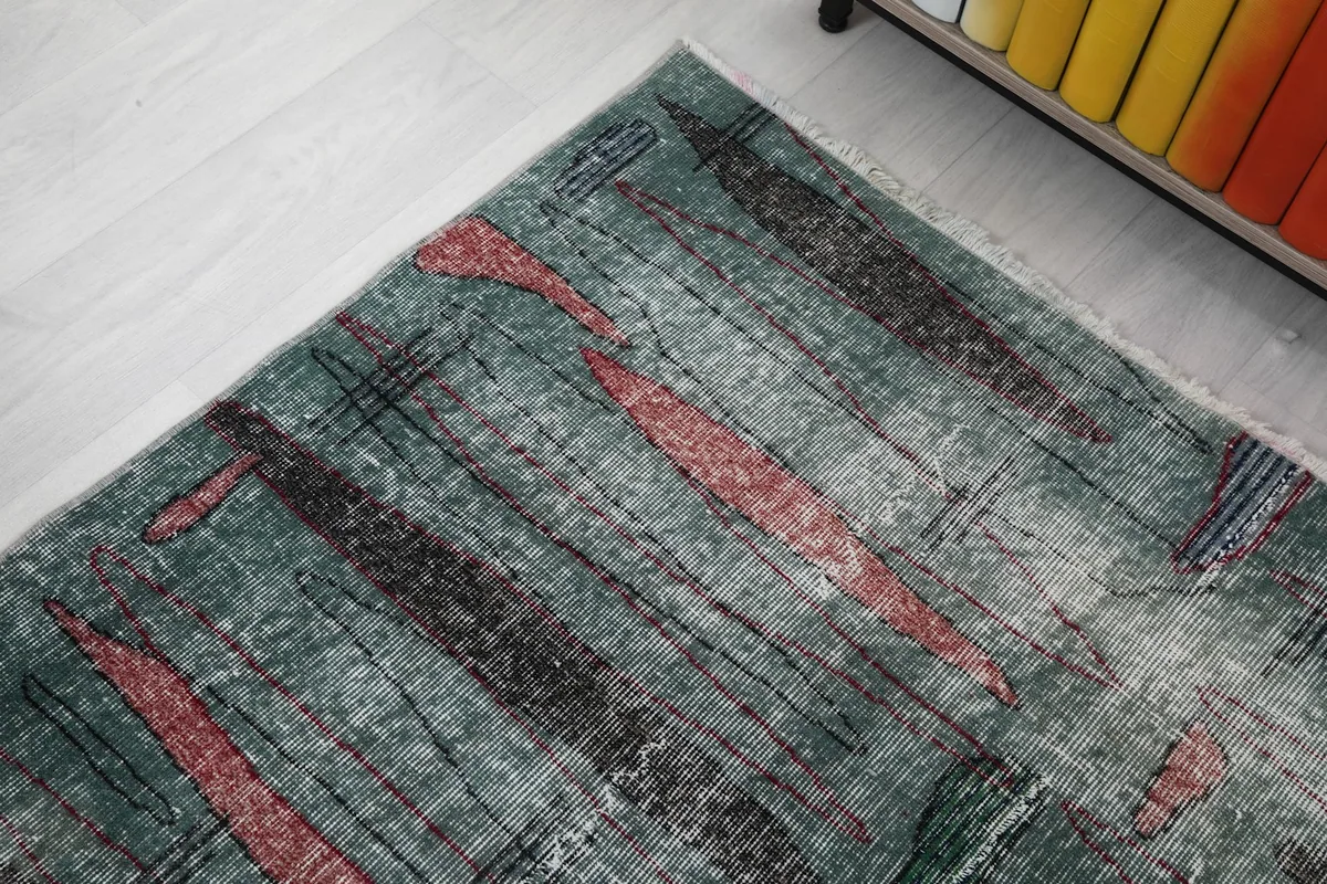 Diagonal view of the rug's abstract design and colors next to a wooden cabinet